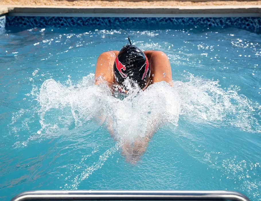 A swimmer in a cap doing breaststroke against the current in a swim spa