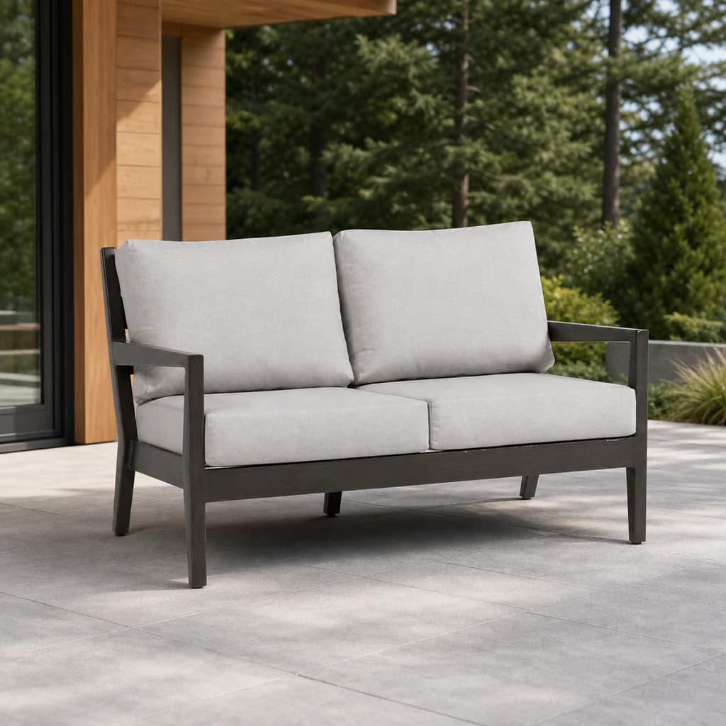 Ratana FN54402 Lucia Love Seat with charcoal aluminum frame and four pale gray cushions on a cedar patio.