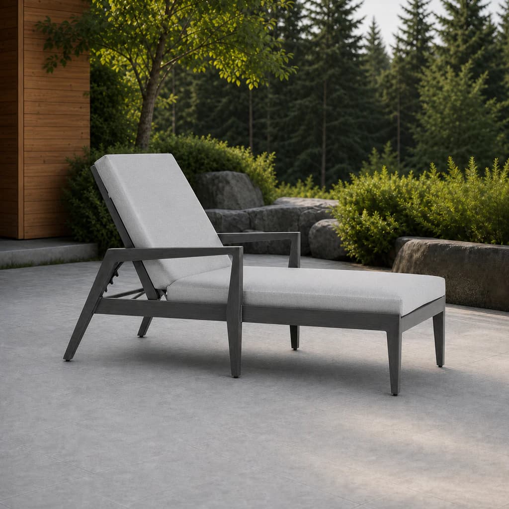 Ratana FN54420 Lucia Adjustable Lounger with charcoal frame and pale gray cushions on a landscaped stone terrace.