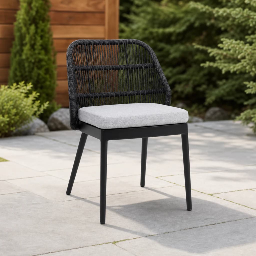 Ratana Las Colinas charcoal open-rope dining side chair with a plain light cushion on a garden patio.
